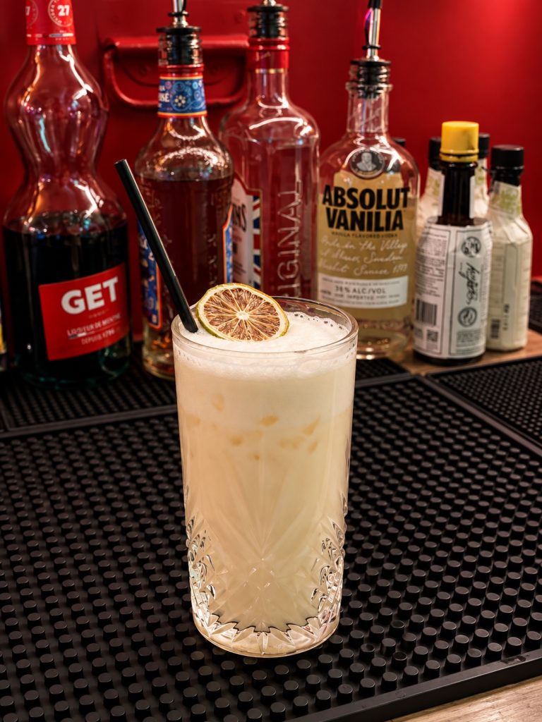 Cocktail de couleur crème servi avec des glaçons et une rondelle d’agrume au Phoenix Bar